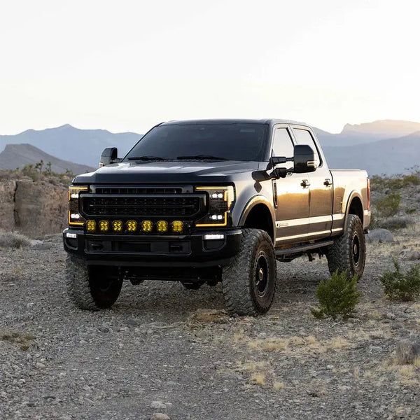 Ford Super Duty parked at sunset with AlphaRex projector headlights and LED tails illuminated