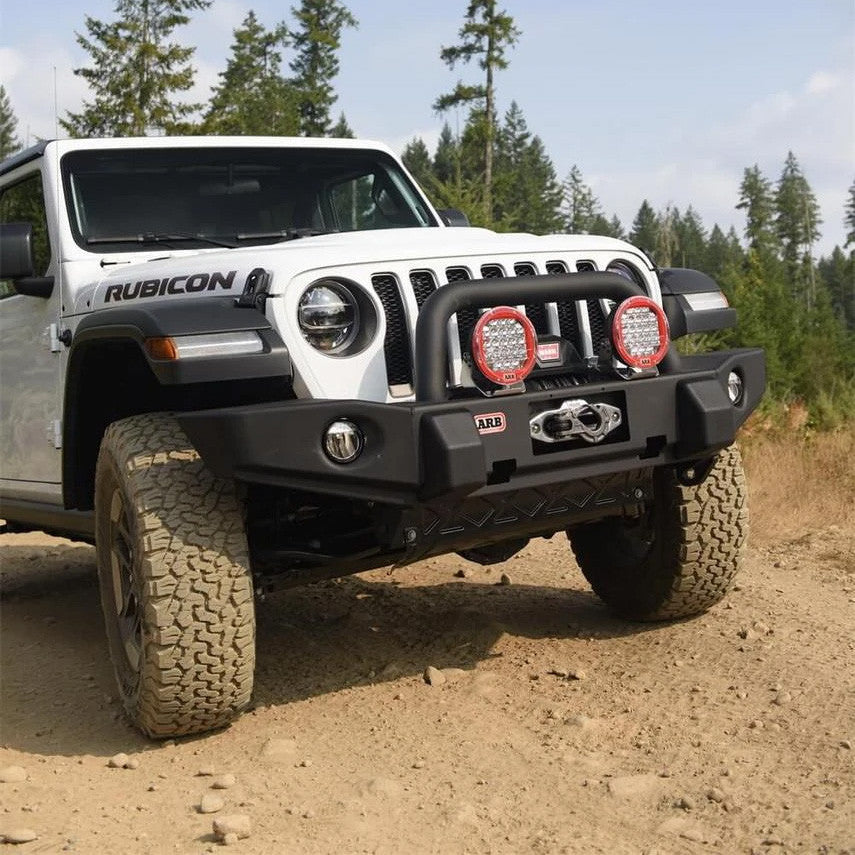 White Jeep Rubicon on a dirt road with trees in the background