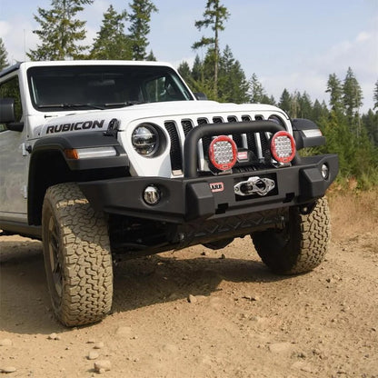 White Jeep Rubicon on a dirt road with trees in the background