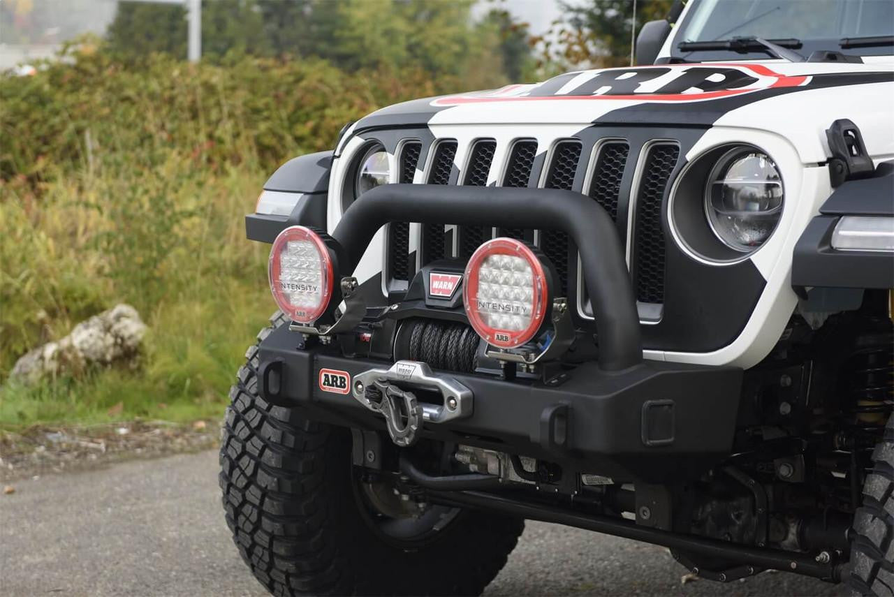 Jeep with off-road bumper and lights on a road