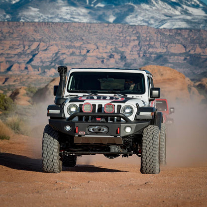 Jeep Wrangler driving on a dirt road with mountains in the background