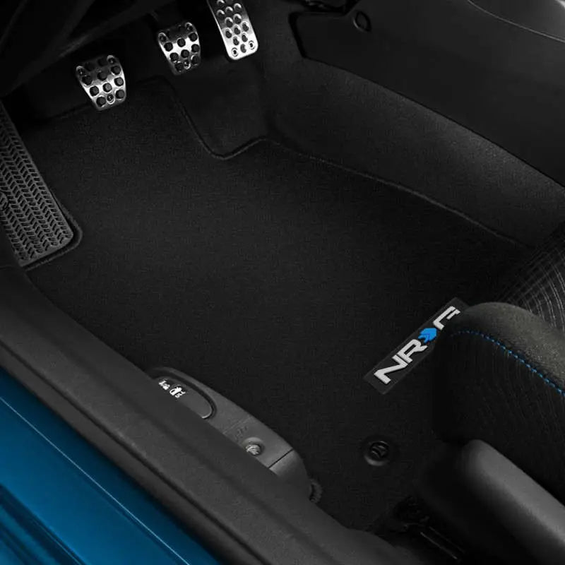 Car interior with black floor mats featuring NRG logo, close-up view.